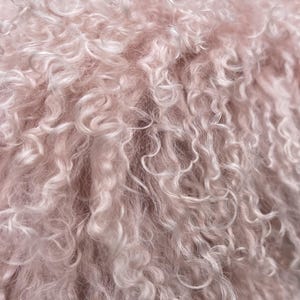 May include: Close-up of a soft, textured material with a curly, wavy pattern. The fabric is a light pink colour, with a fluffy, cloud-like appearance. The texture is dense and appears to be made of many small, individual strands.