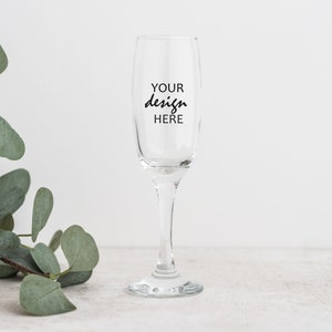 May include: A clear glass champagne flute with the text "YOUR design HERE" printed on the side.