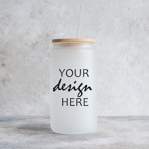 May include: A frosted glass tumbler with a bamboo lid and a straw. The tumbler has the text "YOUR design HERE" printed on it.