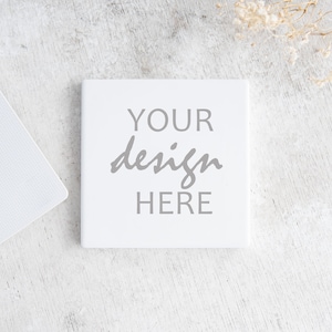 May include: White square tile with the text "YOUR design HERE" in gray lettering on a white wood background.