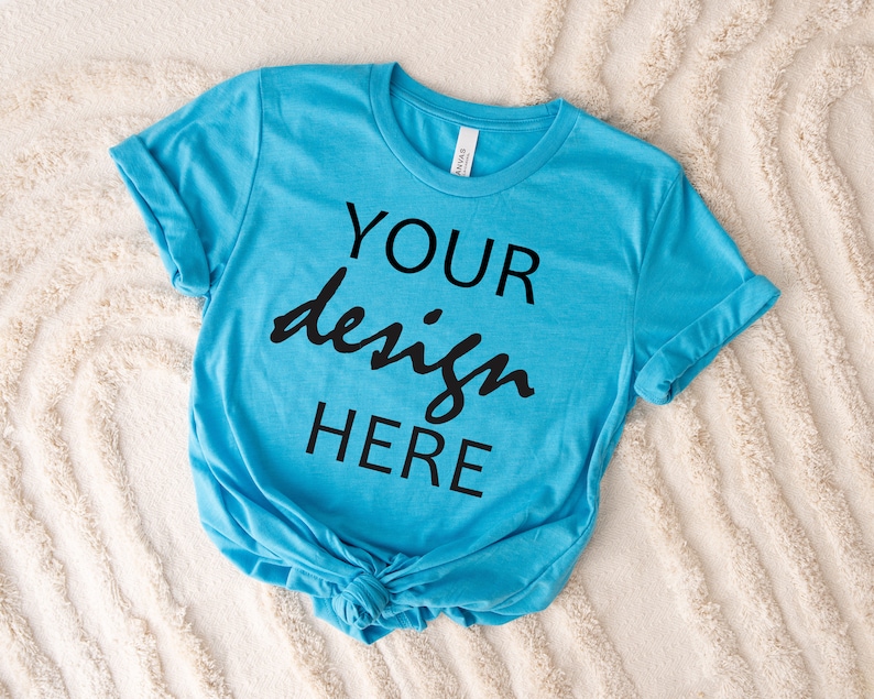 May include: A turquoise blue t-shirt with the text "YOUR design HERE" printed in black on the front.