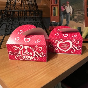 May include: Two red and white Valentine's Day gift boxes with polka dots and hearts. One box says "I Love You" and the other says "Happy Valentine's Day".