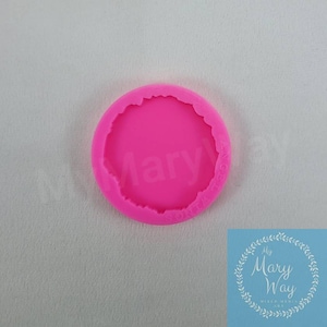 May include: Pink silicone mold with a round, slightly irregular, raised edge. The mold is designed to create a resin piece with a similar shape.