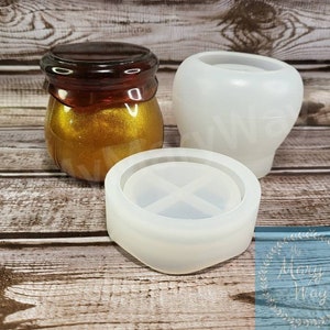 May include: Three silicone molds for crafting. The molds are white and feature a round shape, a jar shape, and a round shape with a cross design.