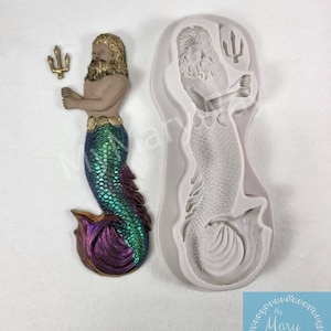 May include: A silicone mold for making a mermaid cake topper. The mold is shaped like a mermaid with a trident, a beard, and a scaly tail. The mold is white and has a smooth surface.
