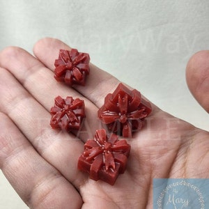 May include: Four small red wax melts shaped like presents with a bow on top.