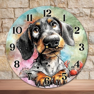 May include: Round wall clock featuring a watercolor illustration of a dachshund dog with big eyes. The clock face has black numerals and hands, with a crab graphic at the 4 o'clock position. The background has a colorful watercolor wash.