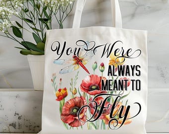 May include: Cream-colored tote bag featuring a watercolor design of red poppies, yellow flowers, and a dragonfly. The bag has the text "You Were Always Meant to Fly" in a decorative font. The bag has two white handles.
