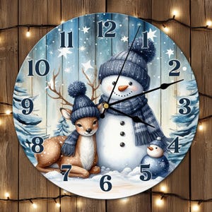May include: Circular wall clock depicting a winter scene with a snowman, deer, and small snowman, all wearing blue hats and scarves. The clock face has large, dark blue numbers and black hands. The background is a snowy forest scene.