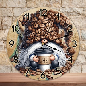 Op de afbeelding: Een ronde klok met een kabouter die een hoed van koffiebonen draagt. De kabouter houdt een kop koffie vast waarop "Coffee" staat. De wijzerplaat van de klok heeft zwarte cijfers en wijzers.