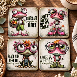 May include: Four square coasters featuring illustrations of pink and green frogs with large eyes and glasses. The text reads: Rings are for fingers not tables, Don't mess up my table!, Place cup here to avoid my wrath, and Use a coaster & no one gets hurt!