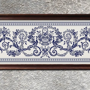 May include: A framed embroidery design featuring a blue floral motif with birds and a basket of flowers. The design is on a white background and is surrounded by a blue border.