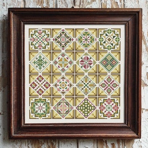 Puede incluir: Un sampler de punto de cruz enmarcado con un patrón repetido de 16 diseños geométricos coloridos en tonos de verde, rojo y amarillo.