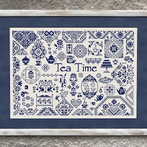 Könnte beinhalten: Gerahmtes Kreuzstich-Kunstwerk mit cremefarbenem Hintergrund und marineblauen Designs. Das Kunstwerk zeigt verschiedene Tee-Motive, darunter Tassen, Teekannen und Kuchen, mit dem Schriftzug "Tea Time" in der Mitte. Der Rahmen ist weiß.