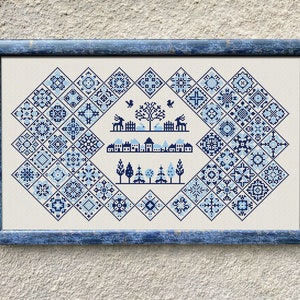 Könnte beinhalten: Ein gerahmtes Kreuzstich-Design mit einer Winterdorfszene mit Häusern, Bäumen und Rehen. Der Hintergrund ist ein blaues und weißes geometrisches Muster.