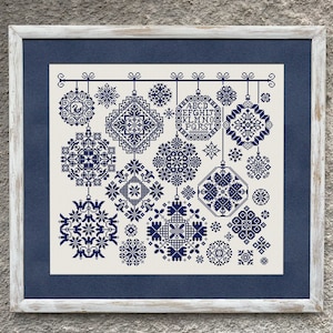 May include: A white framed embroidery design featuring a collection of blue snowflake ornaments with a variety of patterns. The ornaments are hanging from a string and the alphabet is embroidered in the centre.