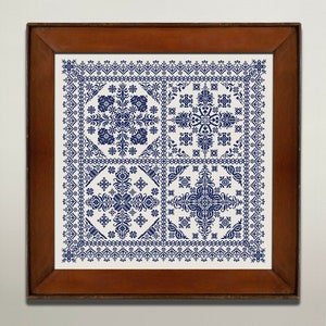 May include: A framed embroidery piece with a white background and a blue geometric pattern. The pattern is made up of four squares, each with a different design.