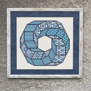 May include: A framed cross-stitch design featuring a blue and white geometric pattern in the shape of a circle. The design is framed in a white wooden frame with a blue mat.