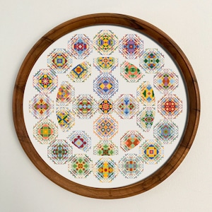 May include: A framed circular piece of artwork featuring a colorful geometric pattern of 30 small squares arranged in a circular pattern. The squares are in shades of red, blue, green, yellow, and white.