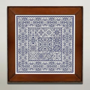 May include: A framed embroidery piece with a blue and white geometric pattern. The design features a central square with a repeating pattern of smaller squares and a border of intricate floral motifs.