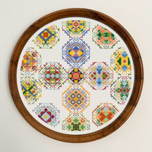 May include: A circular wooden frame with a white background and 15 colorful geometric patterns in a circular design.