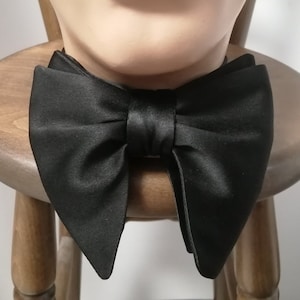 Peut inclure: Un nœud papillon en satin noir avec une pointe pointue à chaque extrémité.
