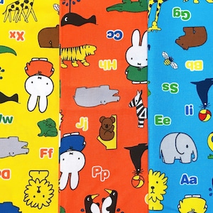 Może przedstawiać: Kolorowa tkanina z postaciami zwierząt z kreskówek, literami i postacią białego królika na żółtym, pomarańczowym i niebieskim tle. Wzór zawiera żyrafy, krokodyle, tygrysy, zebry i słonie. Idealna dla dzieci.