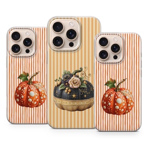 Könnte beinhalten: Drei Smartphone-Hüllen mit saisonalen Motiven. Zwei Hüllen zeigen orangefarbene Kürbisse mit weißen Punkten auf einem vertikal gestreiften orangefarbenen Hintergrund. Die mittlere Hülle zeigt einen schwarzen Kürbis mit Blumen und goldenen Sternen auf gelb gestreiftem Grund.