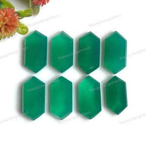 Puede incluir: Ocho cabujones de piedra preciosa verde en forma hexagonal. Las piedras son lisas y pulidas, con una apariencia translúcida.