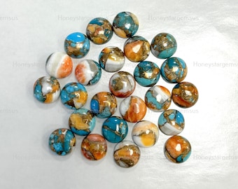 May include: A collection of round, polished gemstones in various colors, including turquoise, orange, white, and gold. The gemstones are scattered across a white surface, showcasing their unique patterns and textures. These stones are ideal for jewelry making.