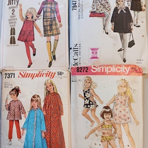 May include: A collection of vintage Simplicity and McCall's sewing patterns for children's clothing. The patterns feature illustrations of girls in dresses, jumpers, and coats. The patterns are from the 1960s and 1970s.