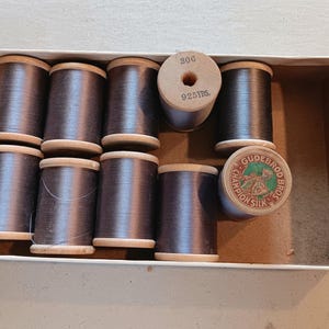 May include: A box of eight spools of black thread, each spool is labeled "Gudebrod Champion Silk" and "80g 925 yds."