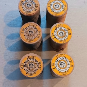 May include: Six spools of vintage Belding Corticelli synthetic thread. The spools have yellow labels with black text and a cat logo. The thread is brown and tan, with yardage of 22 and 30 yards.