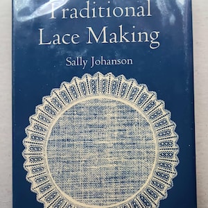 May include: A navy blue book titled "Traditional Lace Making" by Sally Johanson. The cover features a cream-colored lace design on a navy blue background. The book is a guide to lace making.