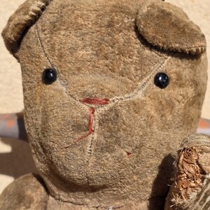 K&ouml;nnte beinhalten: Ein vintage brauner Teddyb&auml;r mit schwarzen Knopfaugen und einer roten gestickten Nase. Der B&auml;r ist aus Pl&uuml;schstoff gefertigt und hat ein abgenutztes Aussehen.