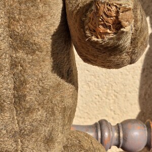 K&ouml;nnte beinhalten: Nahaufnahme eines braunen Teddyb&auml;ren mit einem gro&szlig;en Riss im Arm, der die F&uuml;llung im Inneren freilegt. Der B&auml;r ist aus weichem, pl&uuml;schem Stoff.