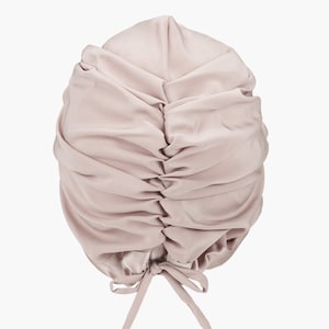 May include: A light pink satin sleep cap with a gathered top and a tie at the back.