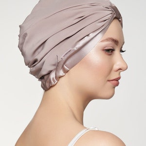 May include: A mauve satin turban with a satin trim and the word "ALMARIA" printed on the trim.