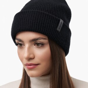 Puede incluir: Un gorro de punto negro con una peque&ntilde;a etiqueta de cuero negro que dice "ALMANIA".