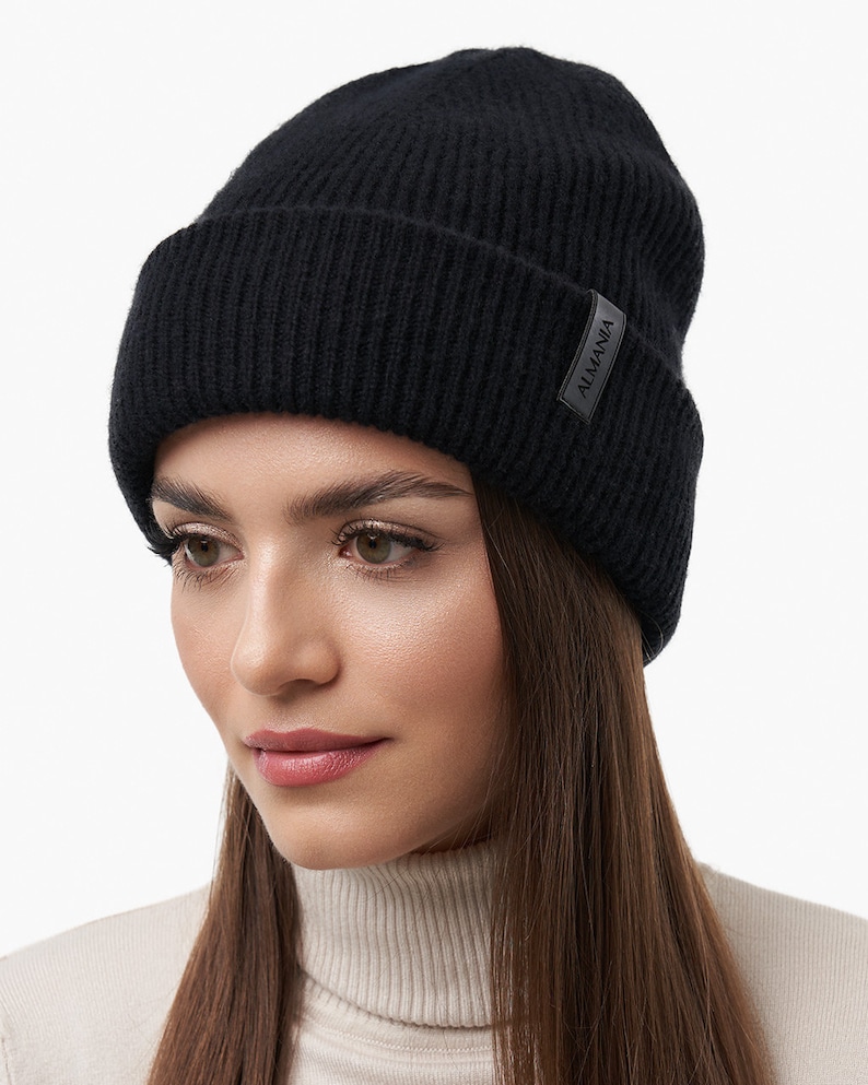 Puede incluir: Un gorro de punto negro con una peque&ntilde;a etiqueta de cuero negro que dice "ALMANIA".