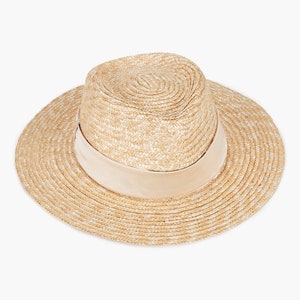 Puede incluir: Un sombrero de paja de ala ancha con una cinta marr&oacute;n claro alrededor de la corona.