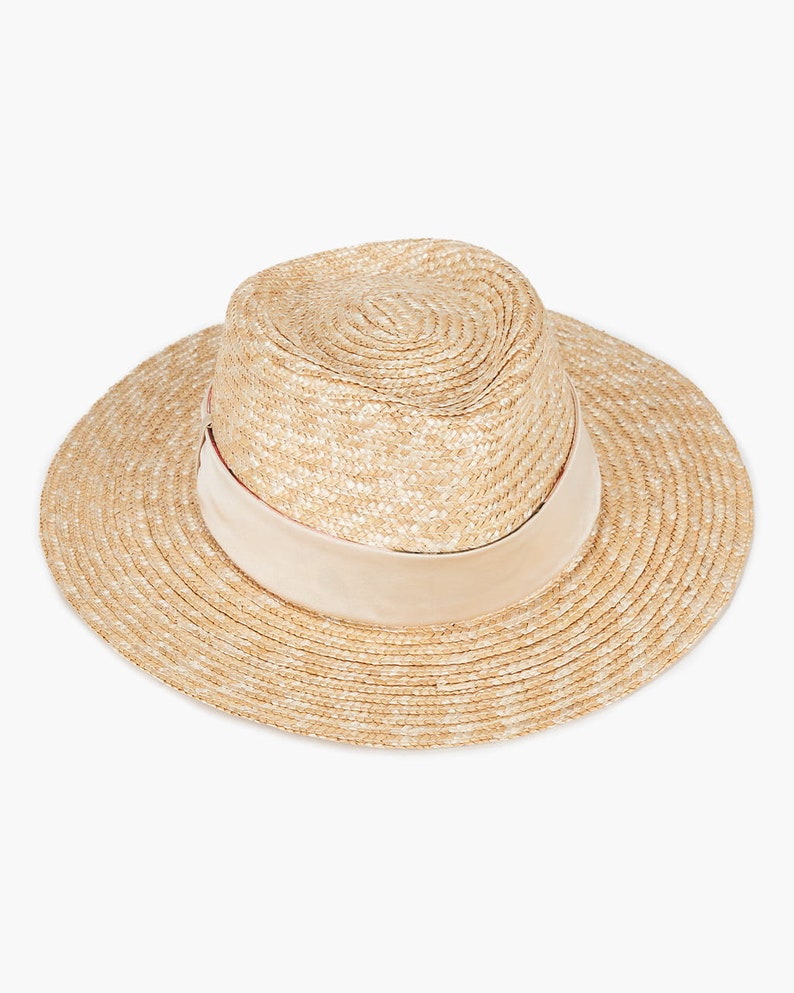 Puede incluir: Un sombrero de paja de ala ancha con una cinta marr&oacute;n claro alrededor de la corona.
