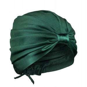 May include: A dark green satin turban with a bow on the side. The turban is made of soft, luxurious fabric and is designed to be worn as a stylish hair accessory.