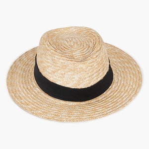 Puede incluir: Un sombrero de paja con una cinta negra. El sombrero es de color marr&oacute;n claro y tiene una textura tejida.