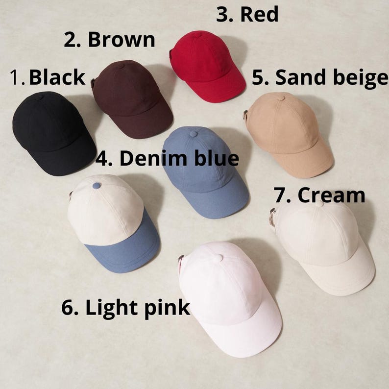 Op de afbeelding: Een verzameling van zeven baseballpetten in verschillende kleuren. De petten zijn zwart, bruin, rood, spijkerblauw, zandbeige, lichtroze en cr&egrave;me. Elke pet heeft een gebogen klep en een verstelbare stoffen band aan de achterkant.