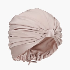 May include: A light pink satin turban with a gathered design and a tie at the back.