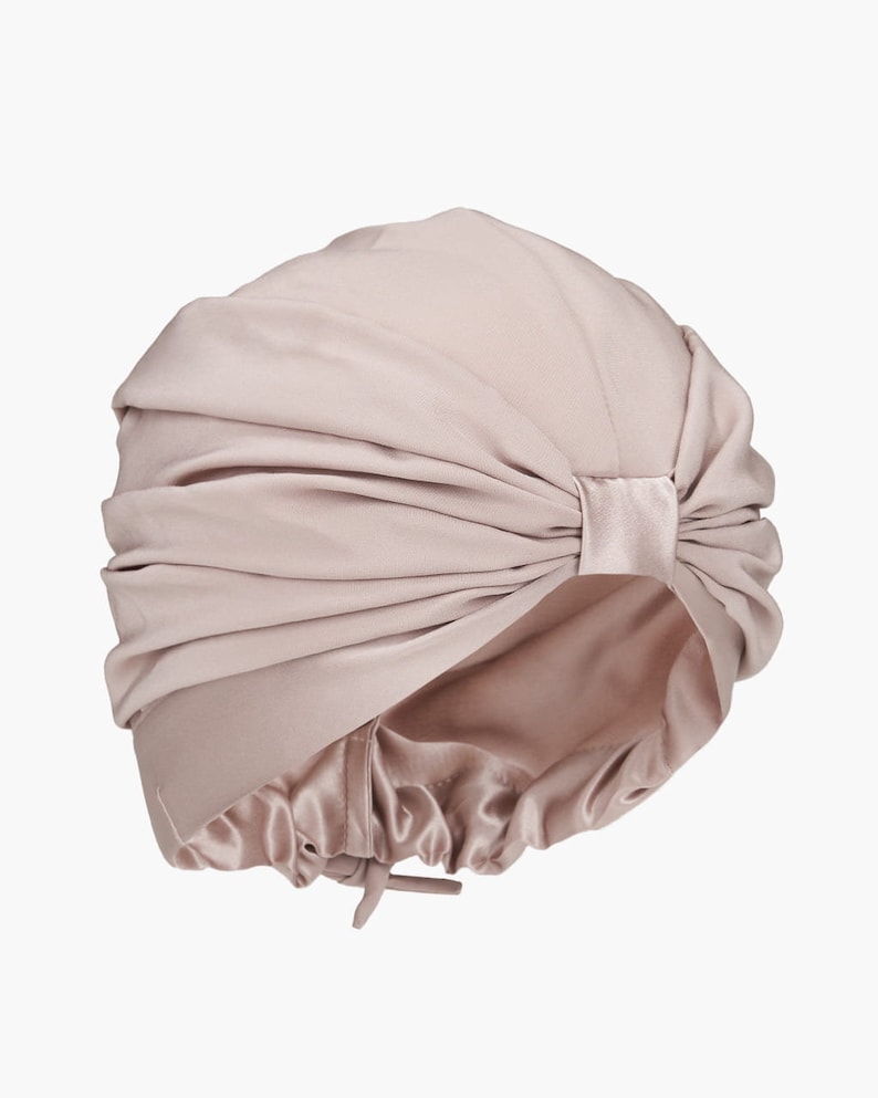 May include: A light pink satin turban with a gathered design and a tie at the back.