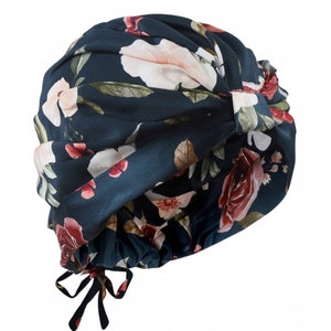 May include: A dark blue turban with a floral print featuring white, pink, and red flowers. The turban has a gathered knot on top and ties at the back.