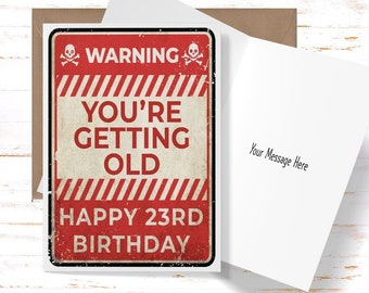May include: Red and white warning sign birthday card with a skull and crossbones on each side. The text reads "WARNING YOU'RE GETTING OLD HAPPY 23RD BIRTHDAY".
