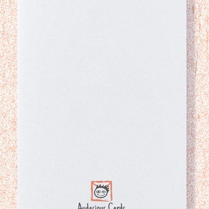 May include: The back of a white card with the text "back of card" at the top. The bottom of the card features a logo with a smiling face inside an orange square, and the text "Audacious Cards" with a website address.